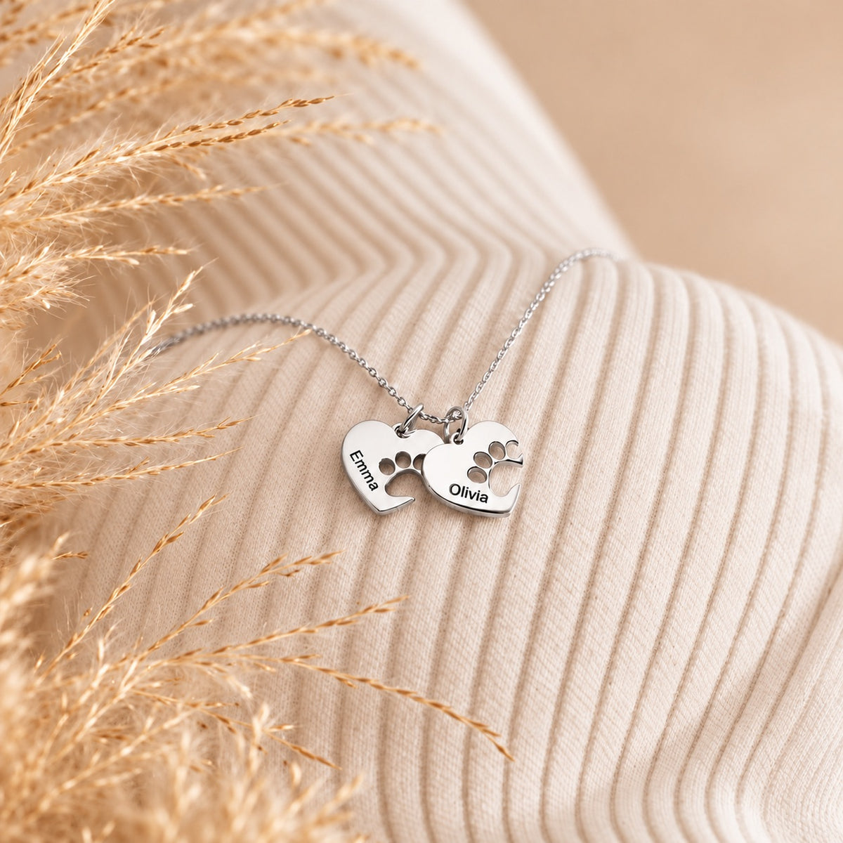 Silver-tone necklace with two paw print heart charms engraved with the names Emma and Olivia