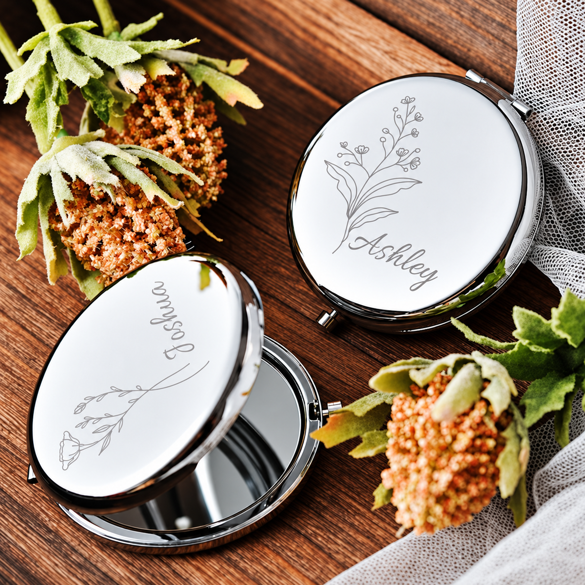 Silver-tone compact mirrors engraved with floral designs and names, including one open mirror