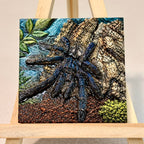 Unframed relief artwork of a blue-toned tarantula against textured bark and leaves on an easel