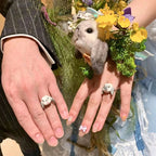 A bride and groom holding hands during their ceremony, wearing bespoke 3D rabbit portrait rings custom hand-sculpted to match the adorable companion nestled in the yellow wedding bouquet, serving as a luxury sentimental keepsake.