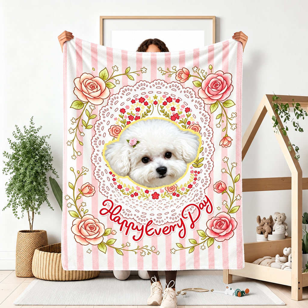 Person holding a pink striped blanket with a small white dog portrait, roses and floral motifs