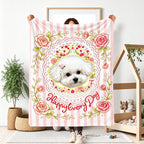Person holding a pink striped blanket with a small white dog portrait, roses and floral motifs