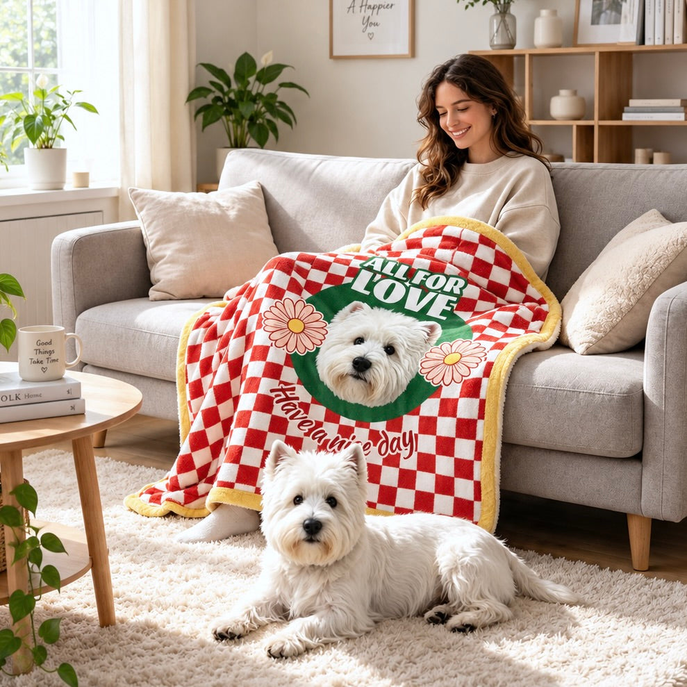 Person using a red checkerboard dog portrait blanket on a sofa with a white dog lying nearby