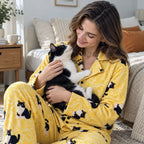 Person in yellow personalized cat pajamas holding a tuxedo cat in a bedroom